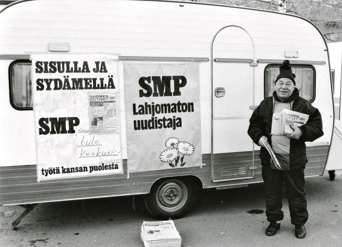 Mikko Vainio vaalityössä asuntovaunun edessä.