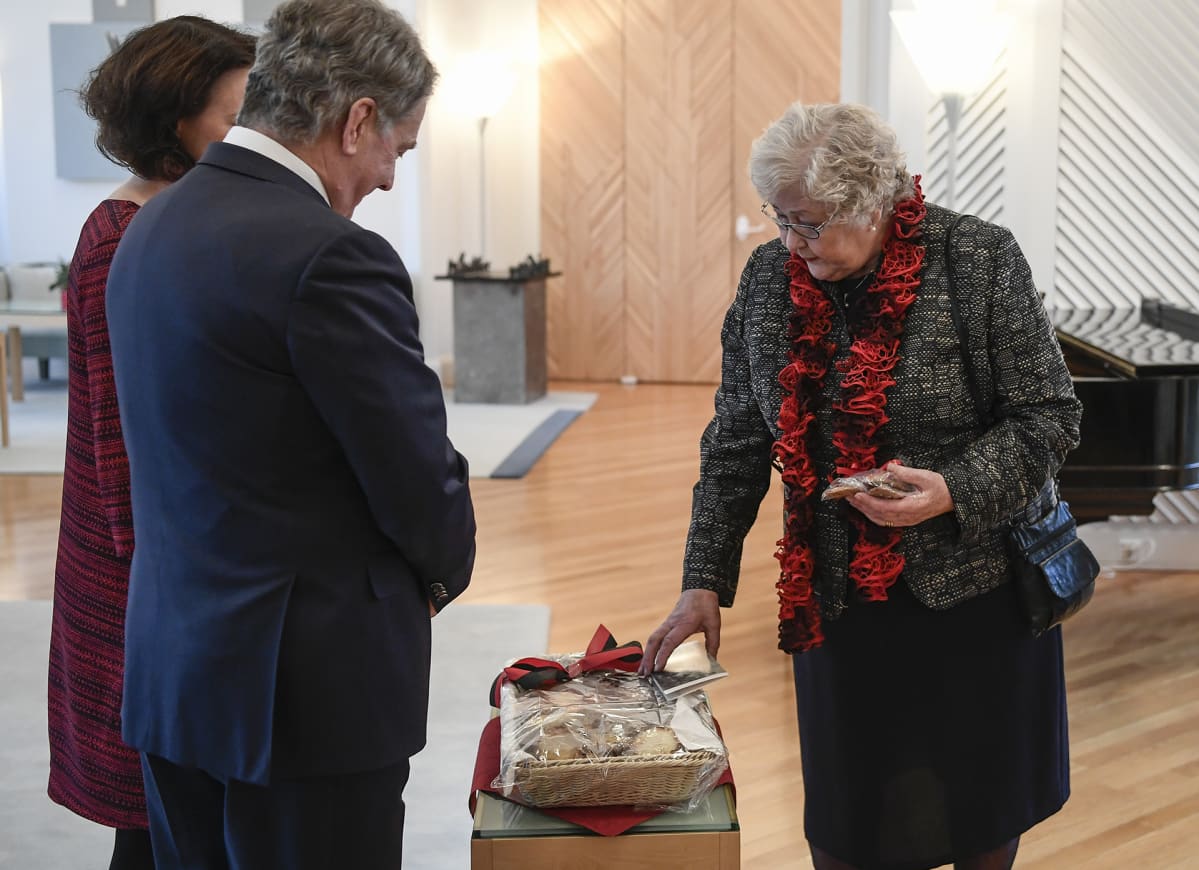 Rouva lahjoittaa karjalanpiirakoita presidenttiparille.