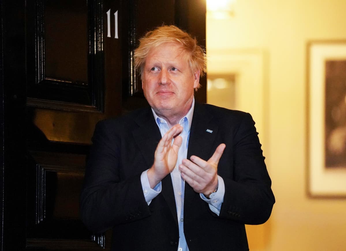 Boris Johnson taputtaa käsiään yhteen ovensuussa.