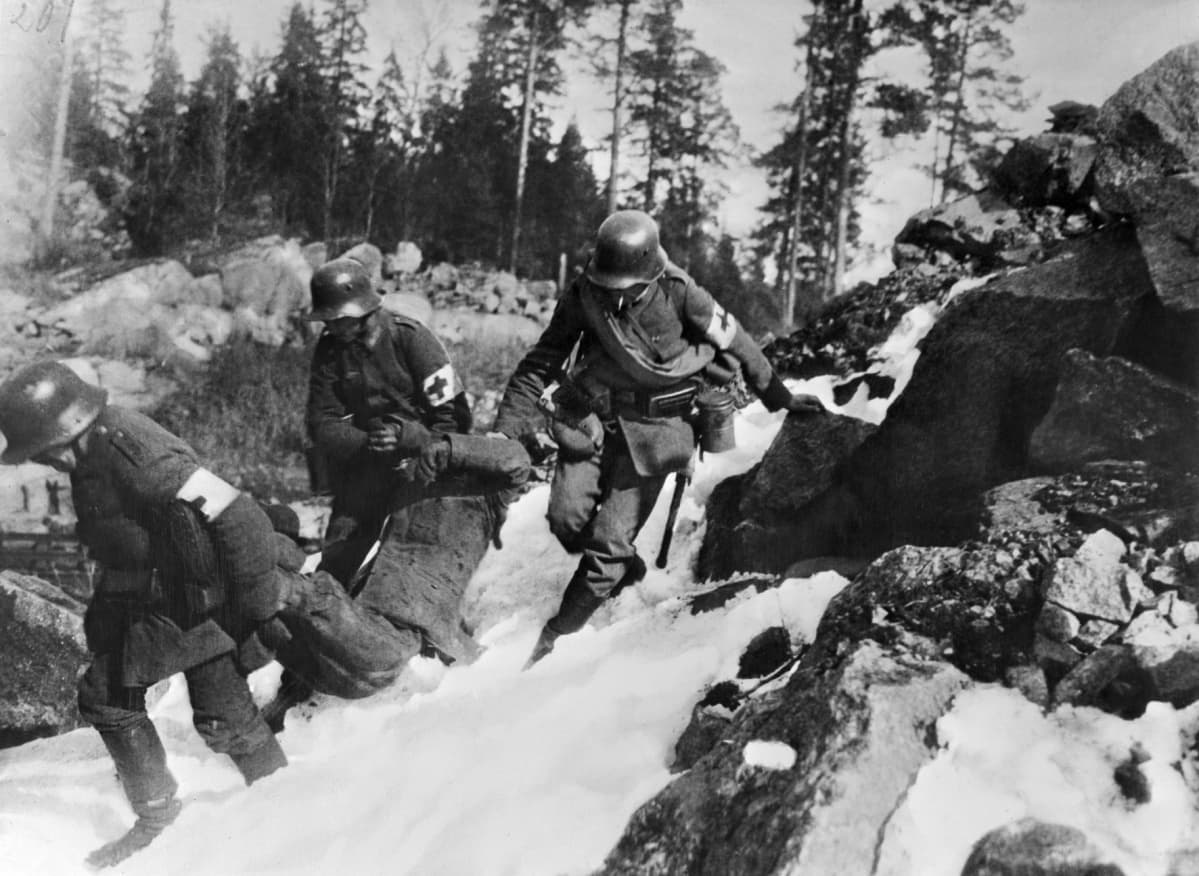 Saksalaiset lääkintämiehet siirtävät haavoittuneen punakaartilaisen suojaan Pasilan kalliolta.