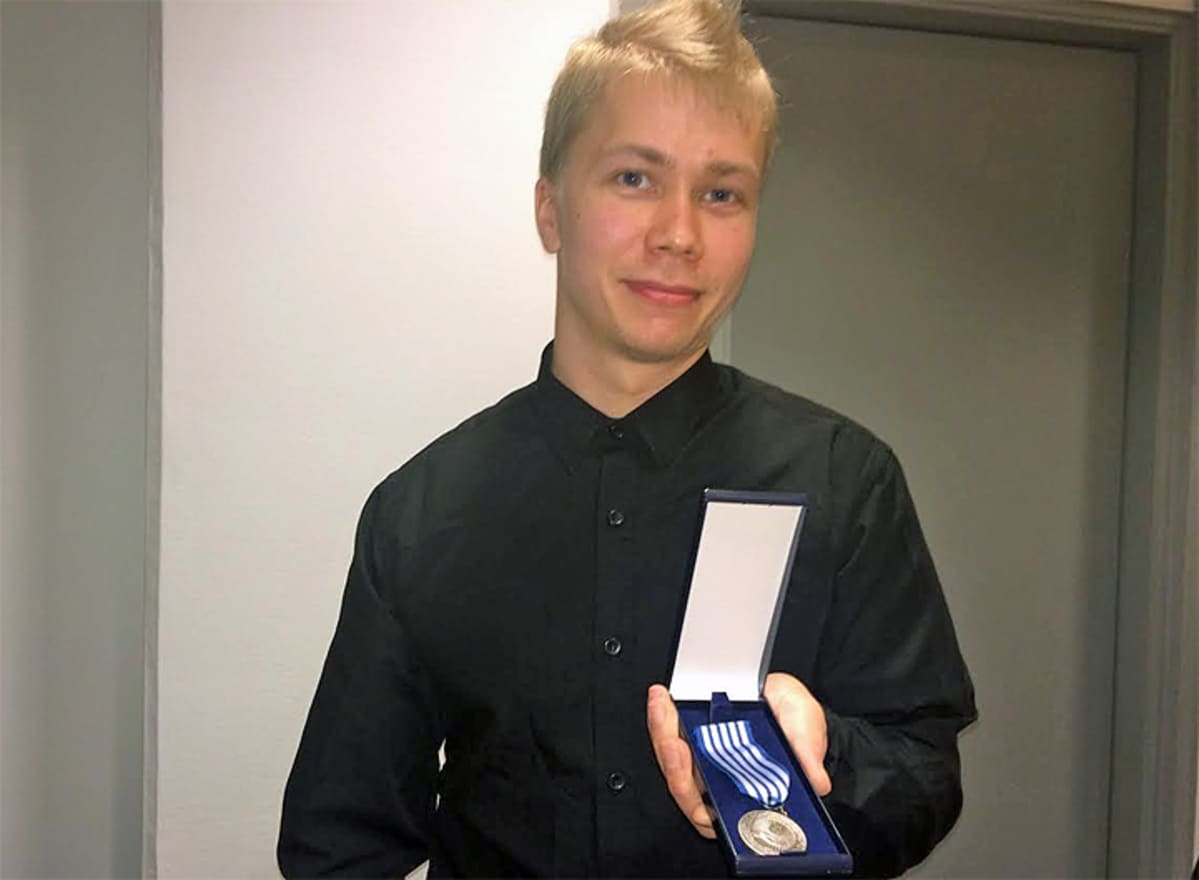 Vartija Tero Ekmark hymyilee kameralle hengenpelastusmitali kädessään.
