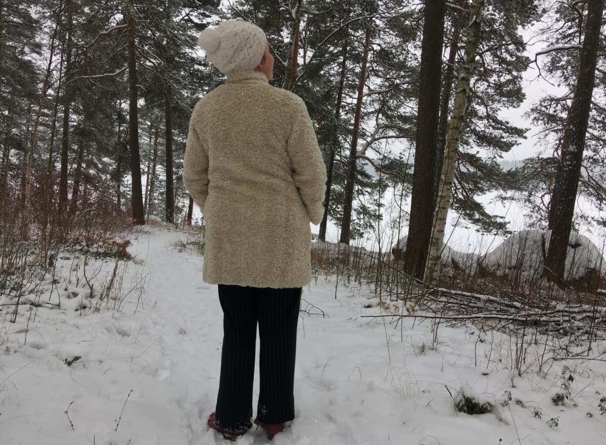Reetta Tourunen katselee puita metsässä.
