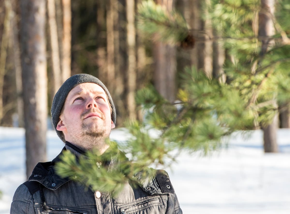 Eetu Raittila katsoo ylöspäin metsässä.