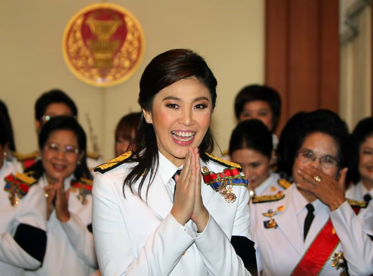 Kuvassa etualalla Yingluck Shinawatra. Hänen kätensä ovat wai-tervehdyksen asennossa.