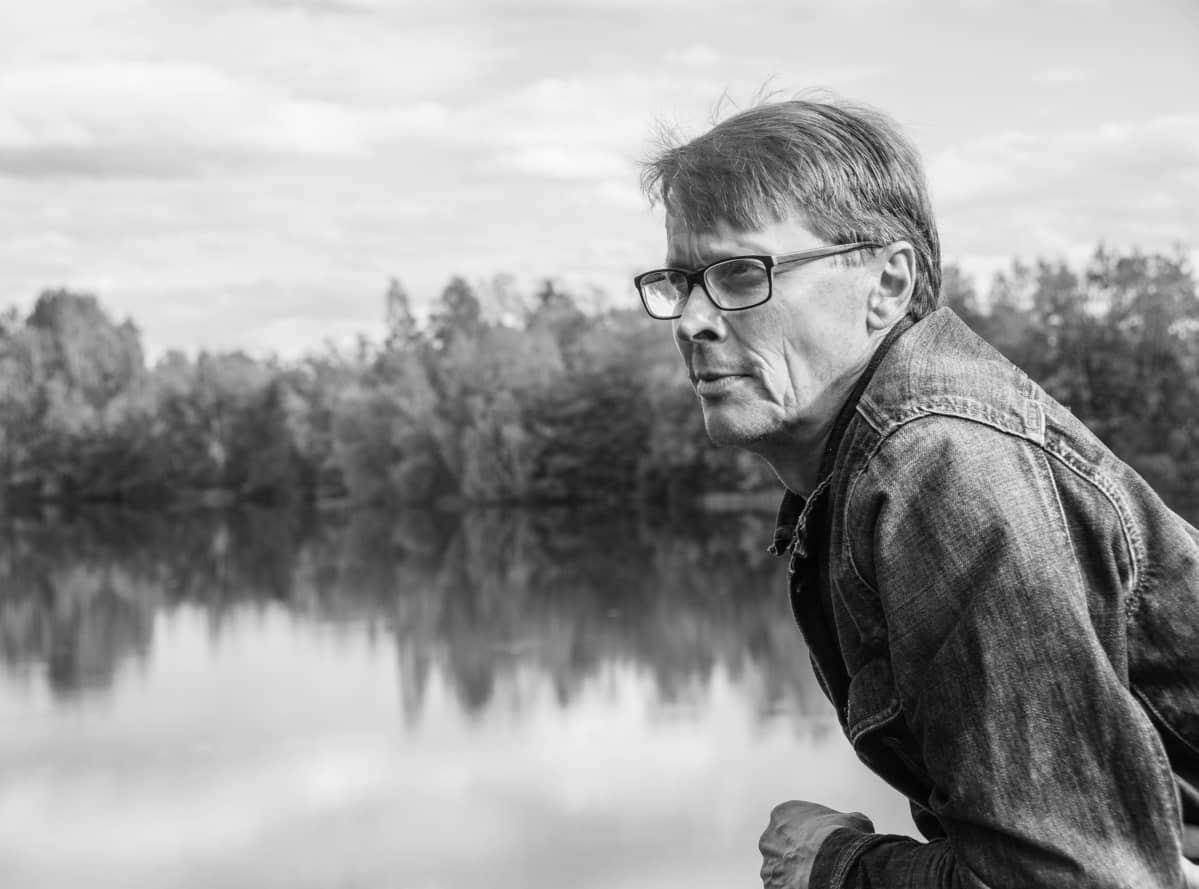 Arto Ranta-Ylitalo nojaa hyppylaiturin kaiteeseen, taustalla kaunis järvimaisema.
