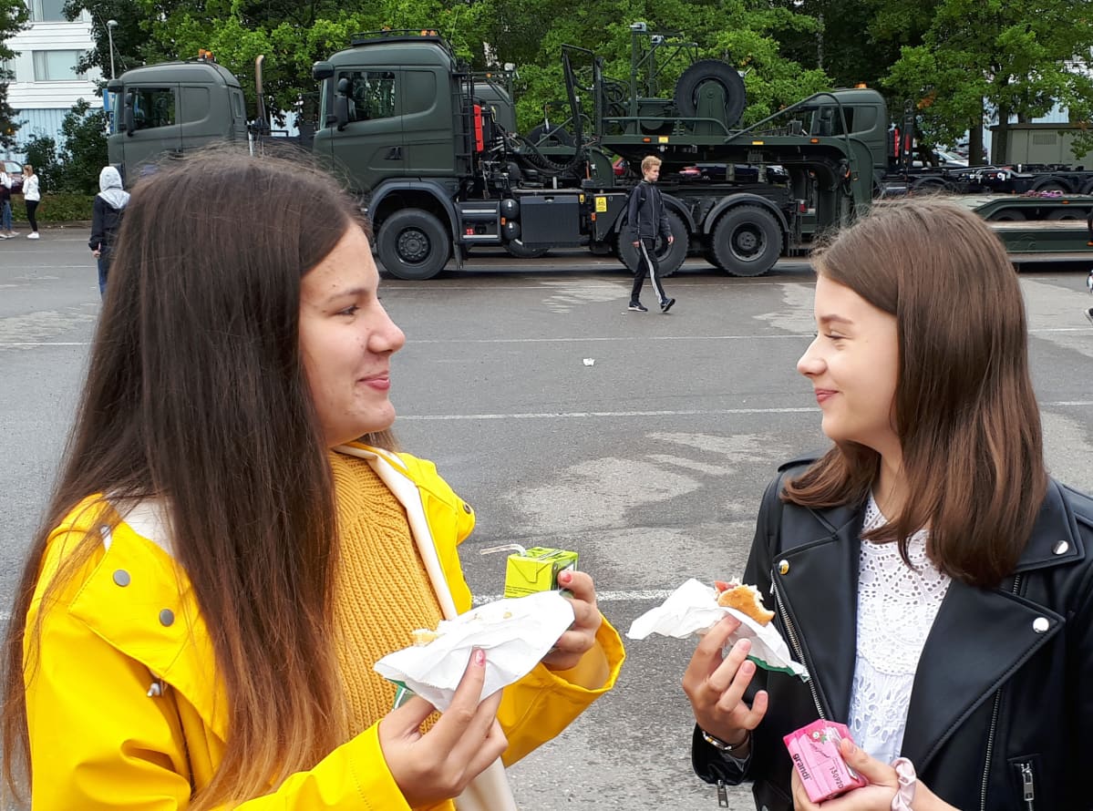 Julia ja Iines syövät lihapiirakkaa parkkipaikalla