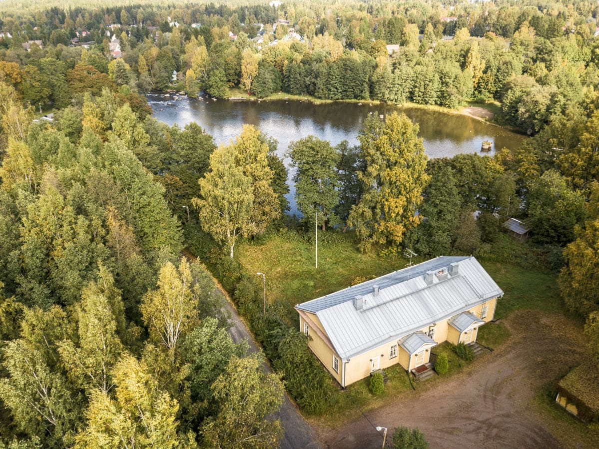 Ilmakuva Kyminlinnan komendantintalosta Kymijoen varressa metsittyneen maiseman ympäröimänä.