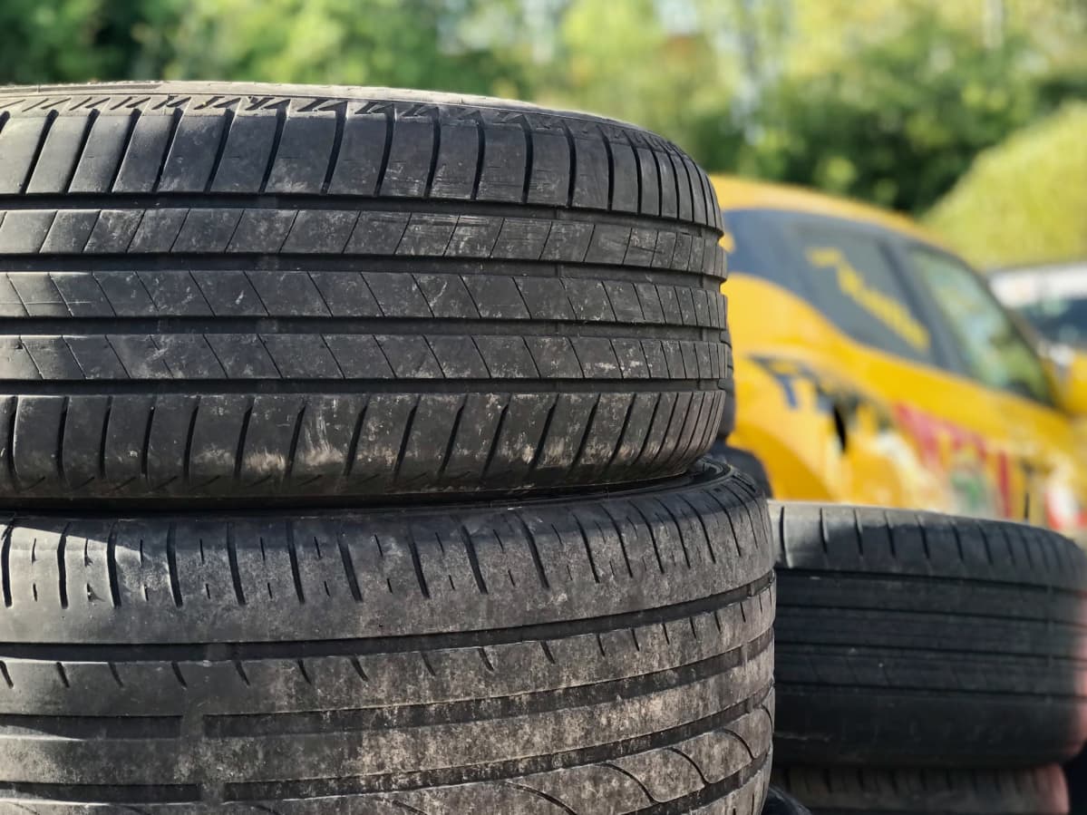 Autonrenkaita kasassa ulkona, takana näkyy keltaista ralliautoa