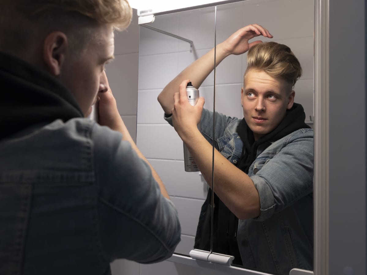 Mikael Huttunen laittaa hiuslakkaa.