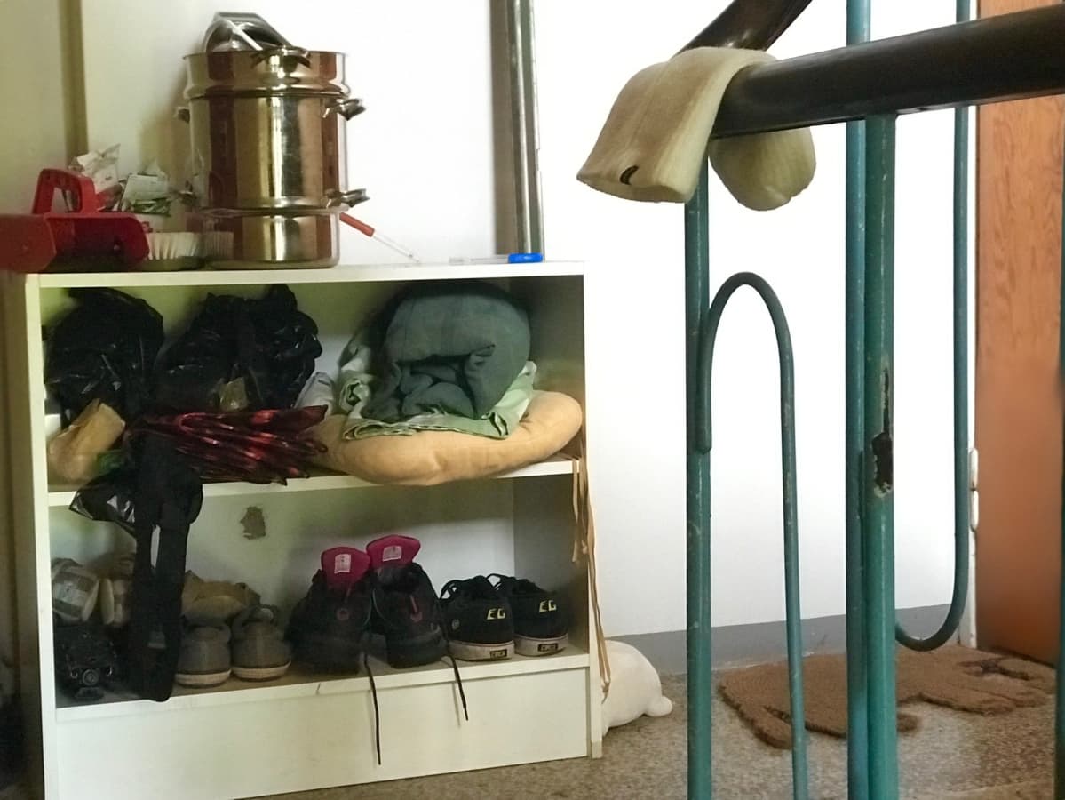 Kenkiä ja mehumaija hyllyllä vanhan kerrostalon rappukäytävässä.