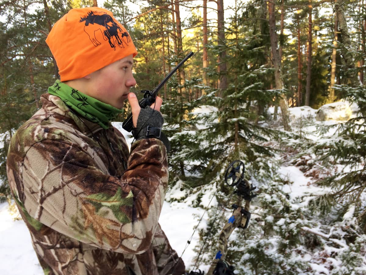 Metsästäjä puhuu radiopuhelimeen metsässä.
