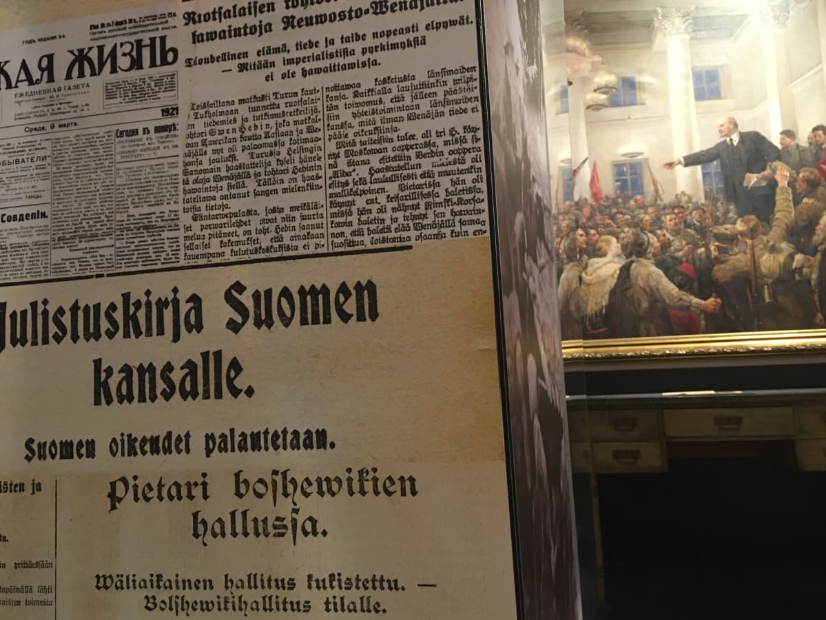 Vanhoja lehtileikkeitä Lenin-museon pylväässä. Taustalla maalaus, jossa Lenin puhuu kansalle.