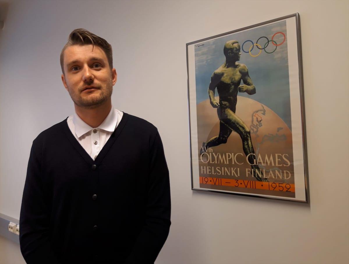 Mies seisoo taulun vieressä.