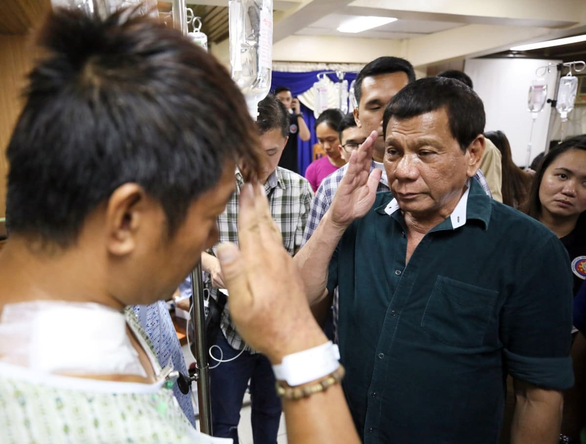 Duterte tekee kunniaa sotilaalle, joka on sairaalan vaatteissa.