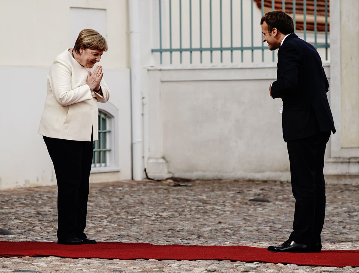 Kuvassa Angela Merkel toivottaa Emmanuel Macronin turvaetäisyyden päästä tervetulleeksi.