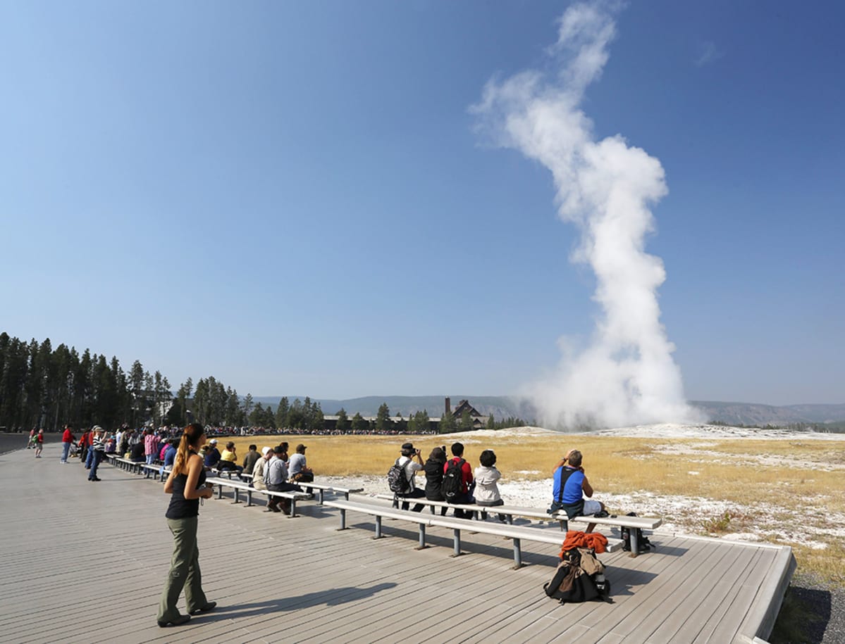 Turistit seuraavat Old Faithful geysirin purkausta Yellowstonen kansallispuistossa Yhdysvalloissa.