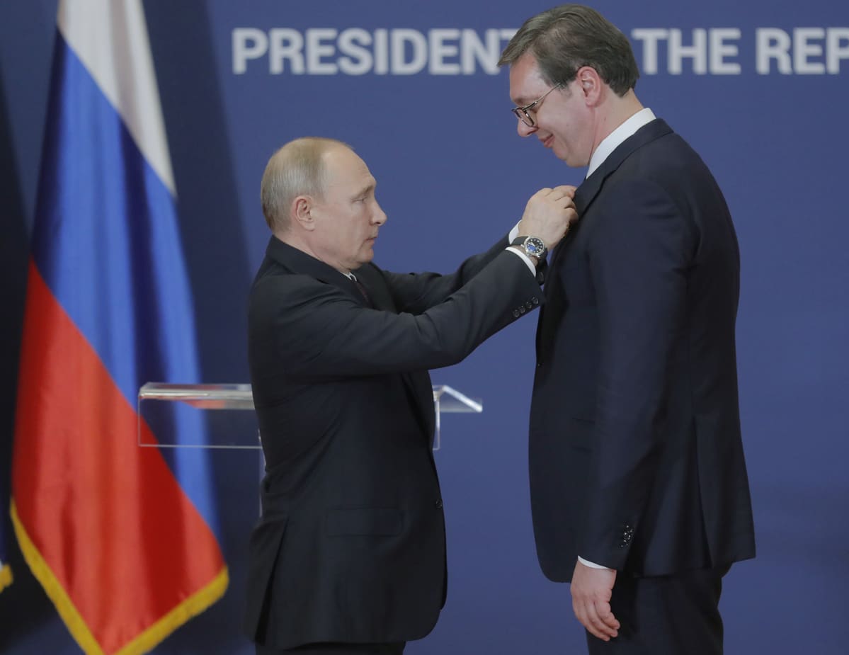 Vladimir Putin kiinnittää kunniamerkin Alexandar Vucicin rintaan.