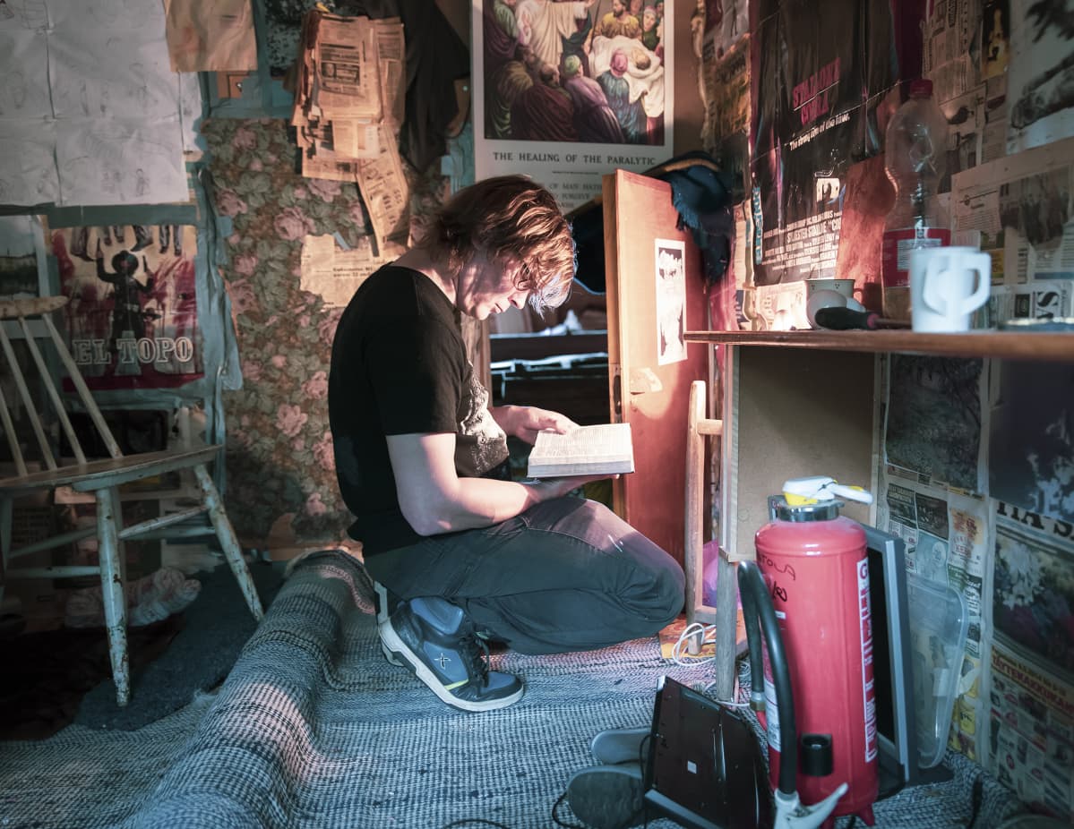 Lauri Ainala on kyykyssä ullakkohuoneessa ja lukee kirjaa.