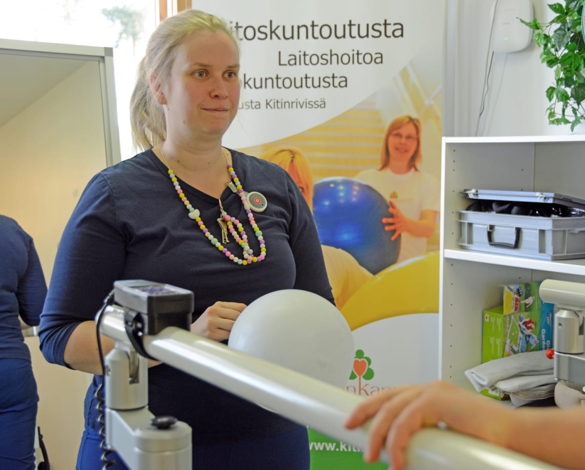 Fysioterapeutti Riina Puutio pallottelee Eemi Laurilan kanssa kävelymatolla.