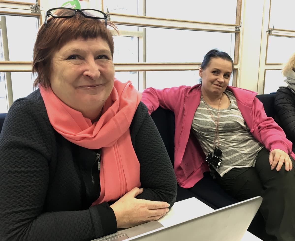 Projektipäällikkö Anne Haapalehto ja nuoriso-ohjaaja Piia Kallonen istuvat sohvalla koulun aulatilassa ja hymyilevät kuvaajalle.
