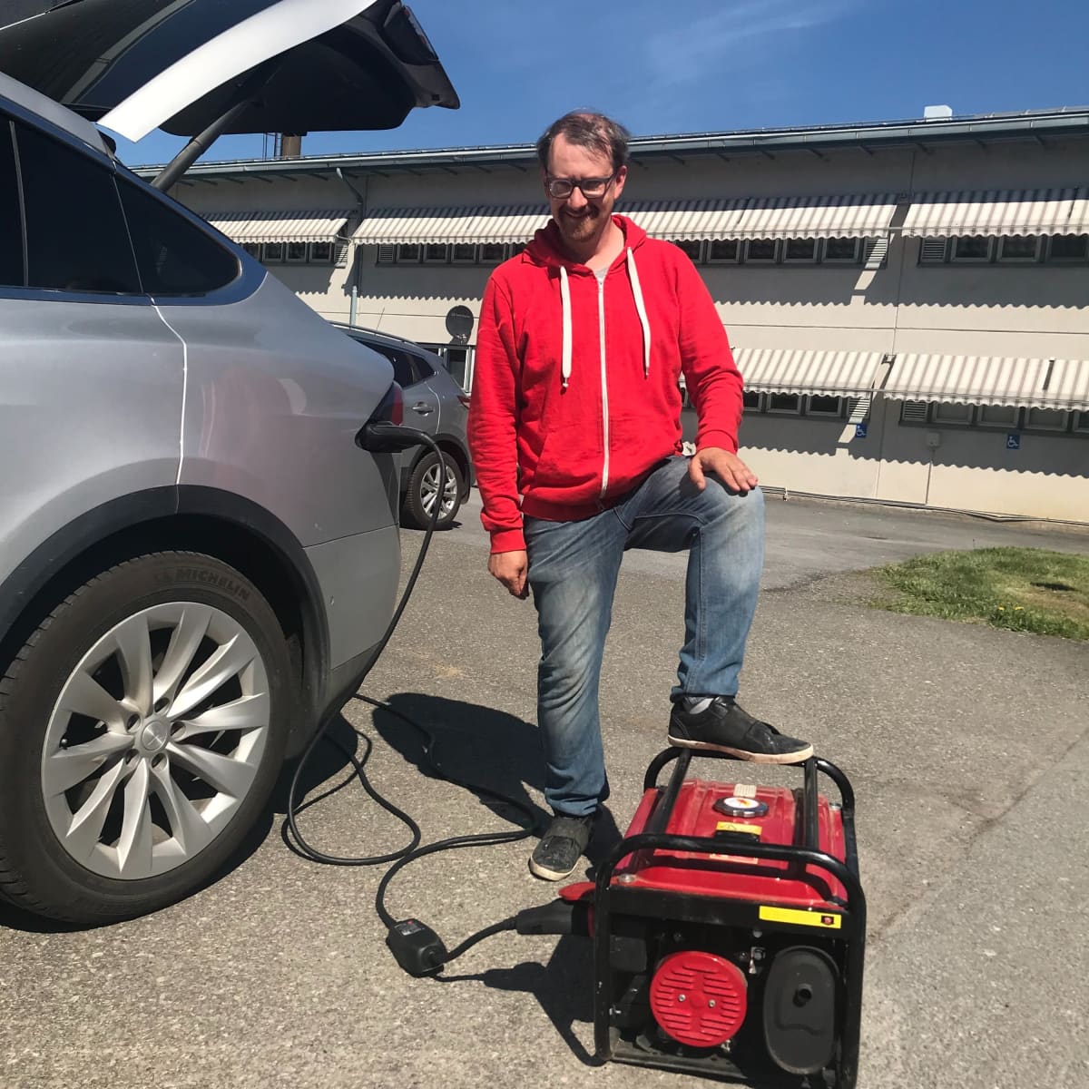 Mies lataa sähköautoa aggregaatilla