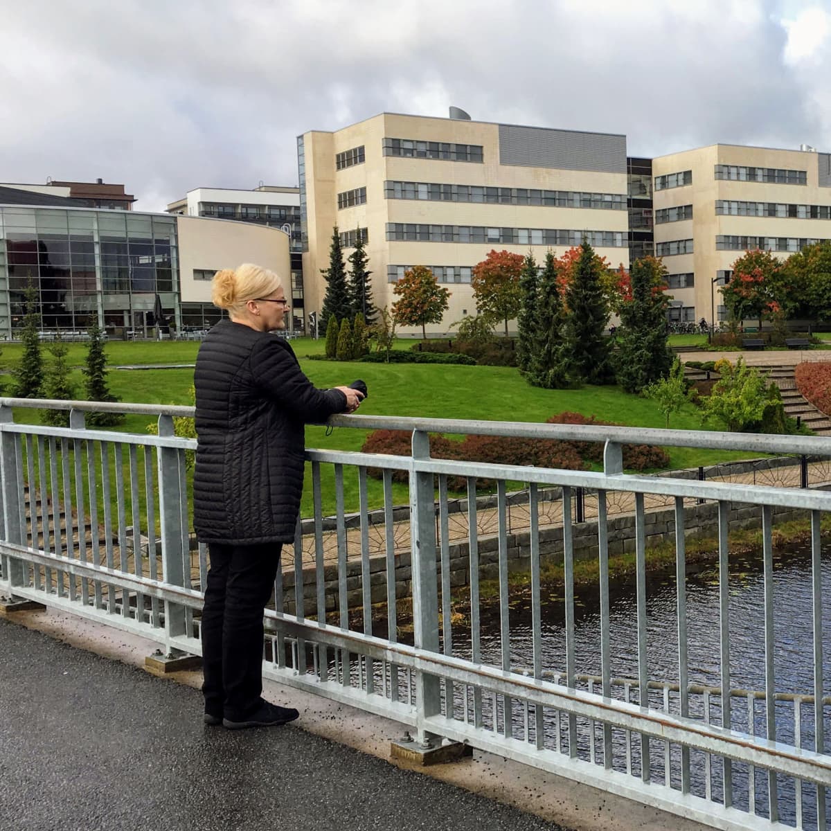 Aino Peltonen seisoo sillalla ja katsoo kauas mietteliäästi.
