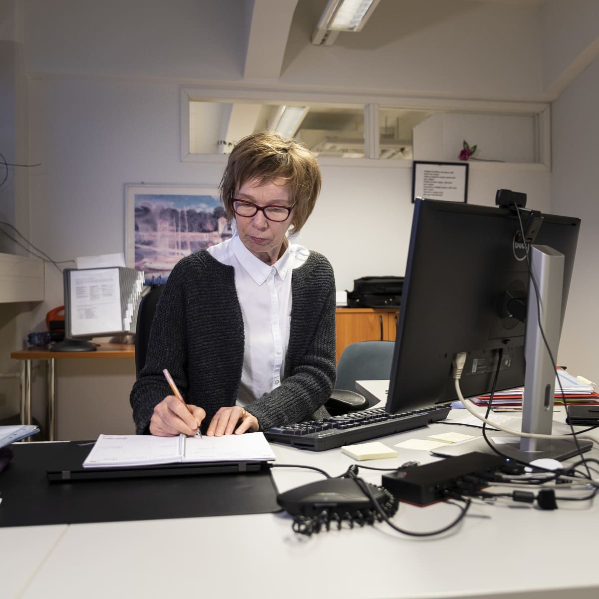 Pirkko Kivistö kirjaa muistiinpanoja kalenteriinsa omassa työpisteessään.
