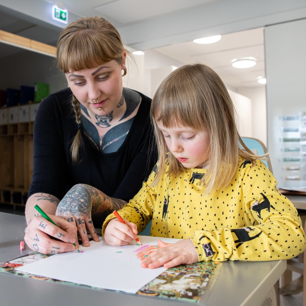 Kaisa Niskanen värittää paperia tyttärensä kanssa.