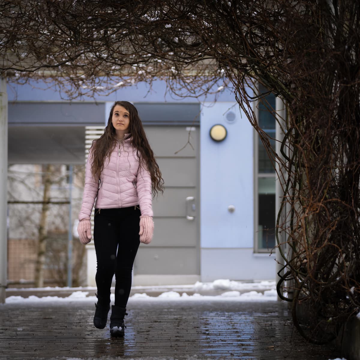 Opiskelija Janika Angelsola kävelee kerrostalon pihalla.