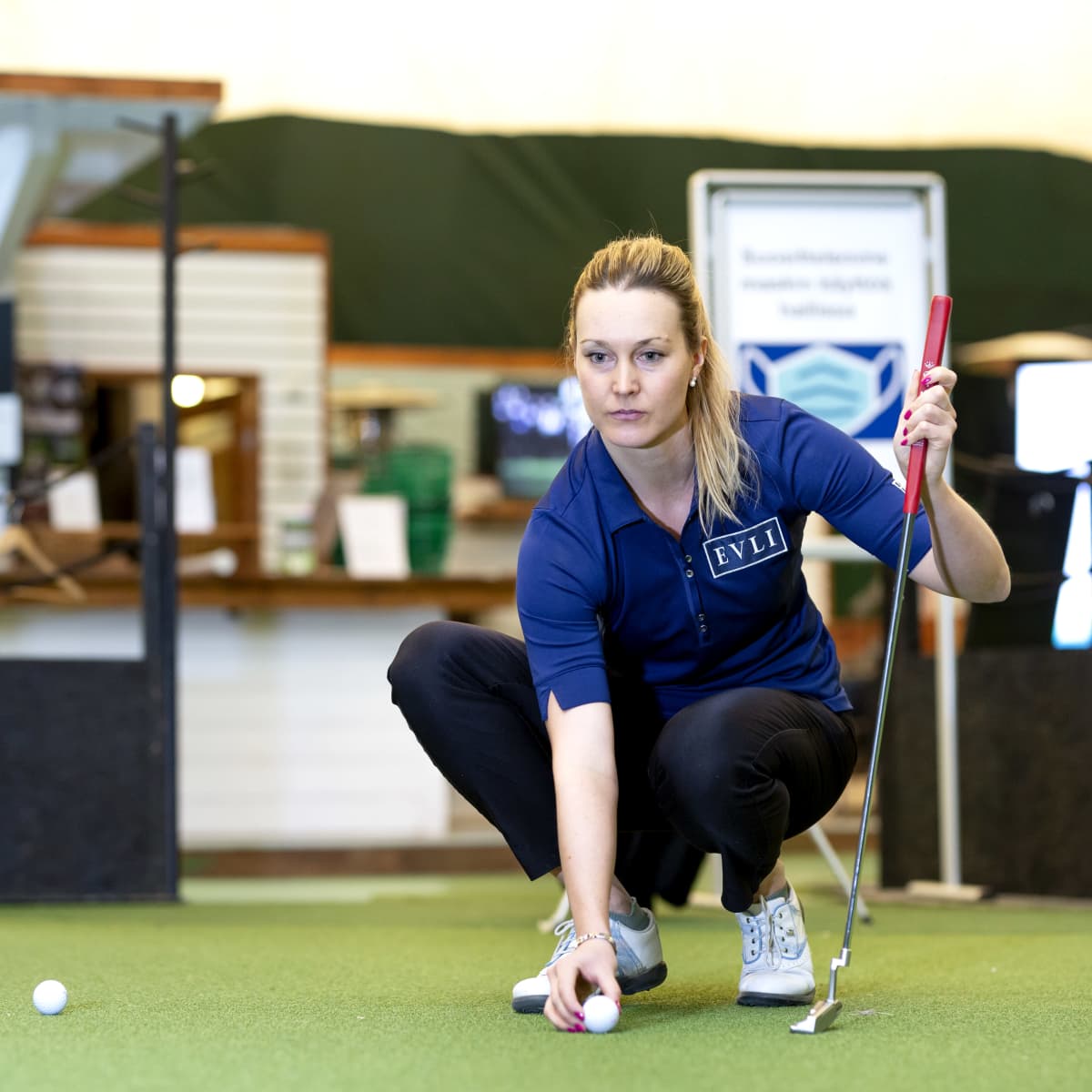 Sanna Nuutinen puttaamassa golfhallissa.