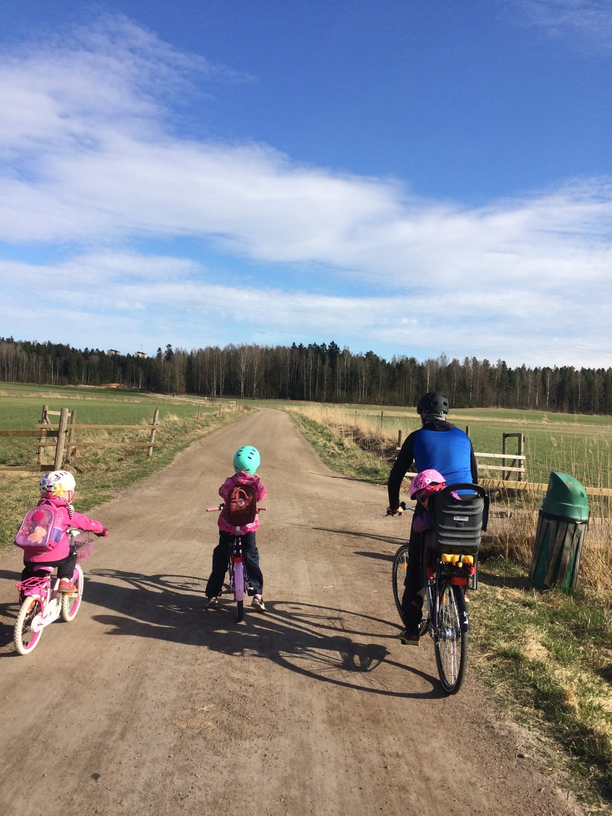 Isä ja kolme lasta pyöräretkellä.