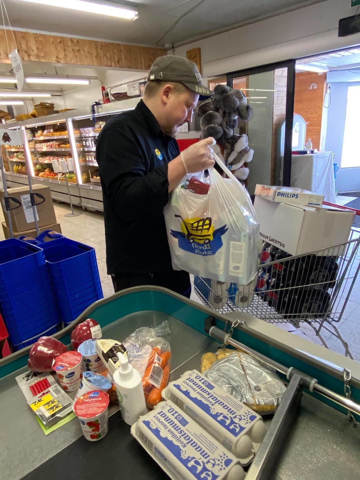 Näätämön Nord1-Marketin kauppias Juha Kekäle pakkaa kotiinkuljettavaksi ruokaostoksia.