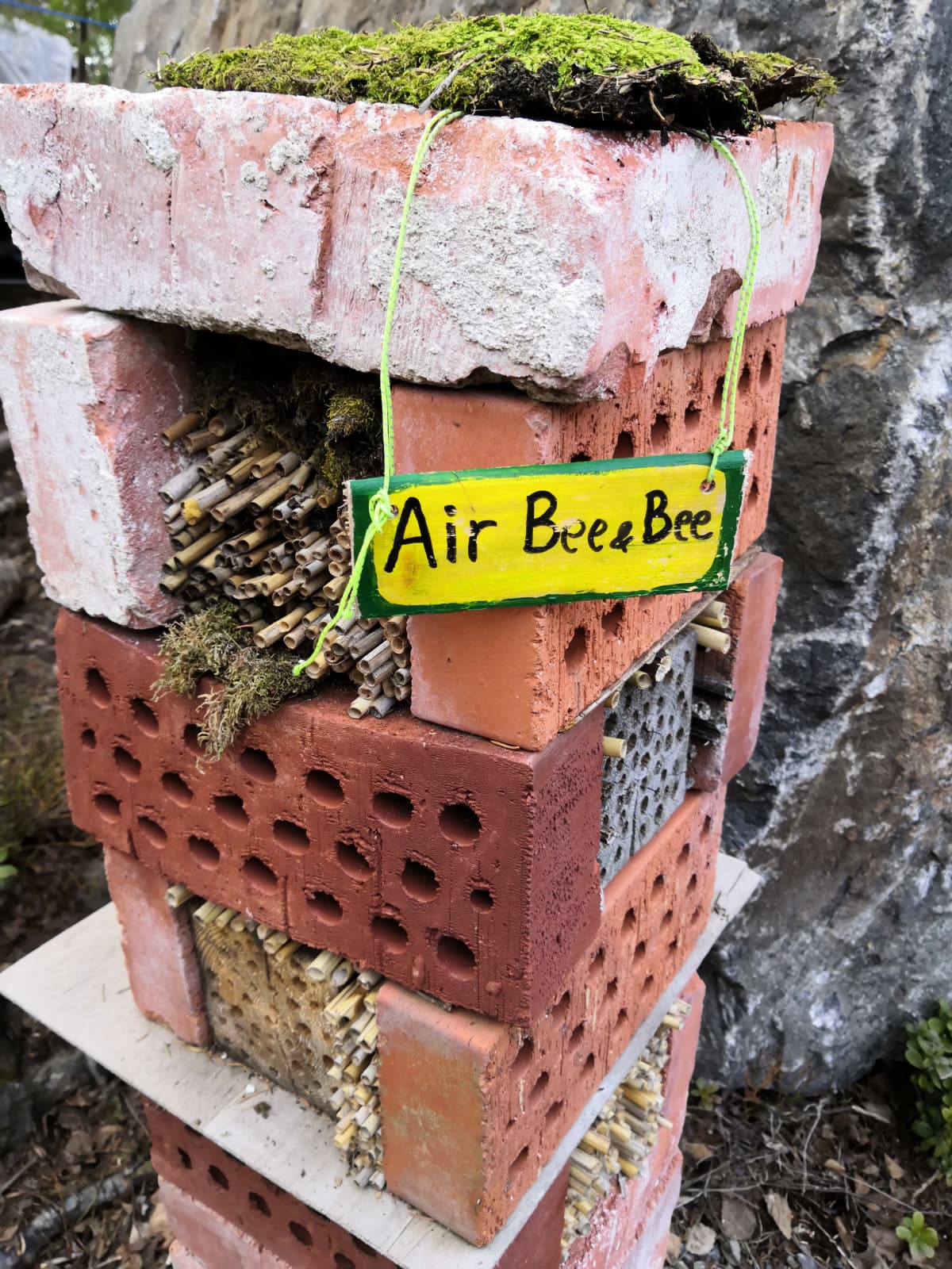 Tiilistä koottu hyönteishotelli bee&bee-kyltillä.