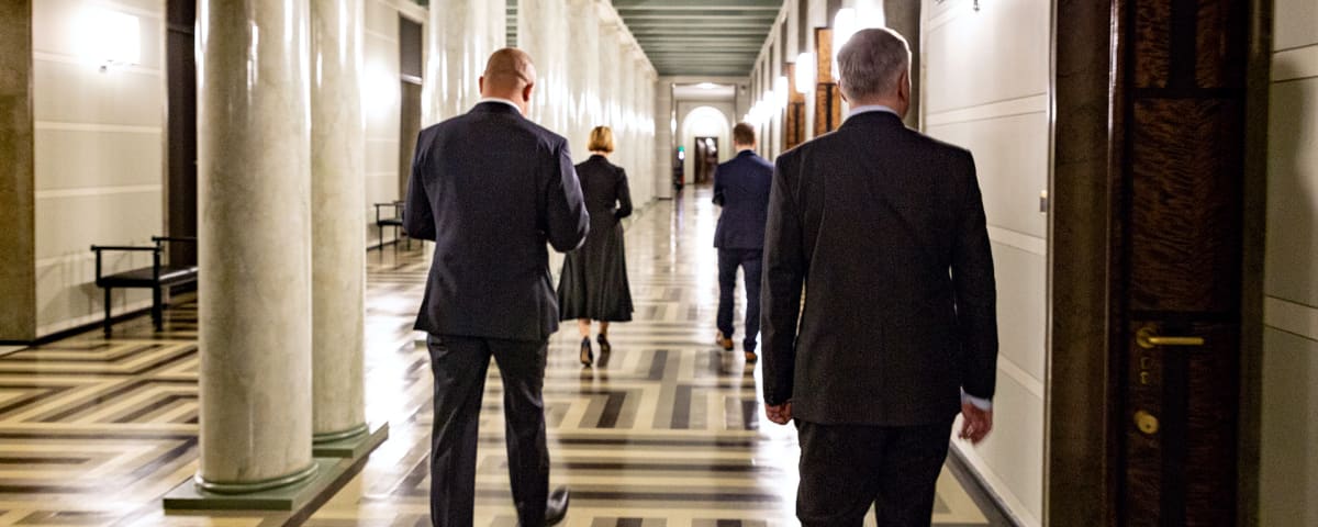 miehiä eduskuntatalon käytävillä