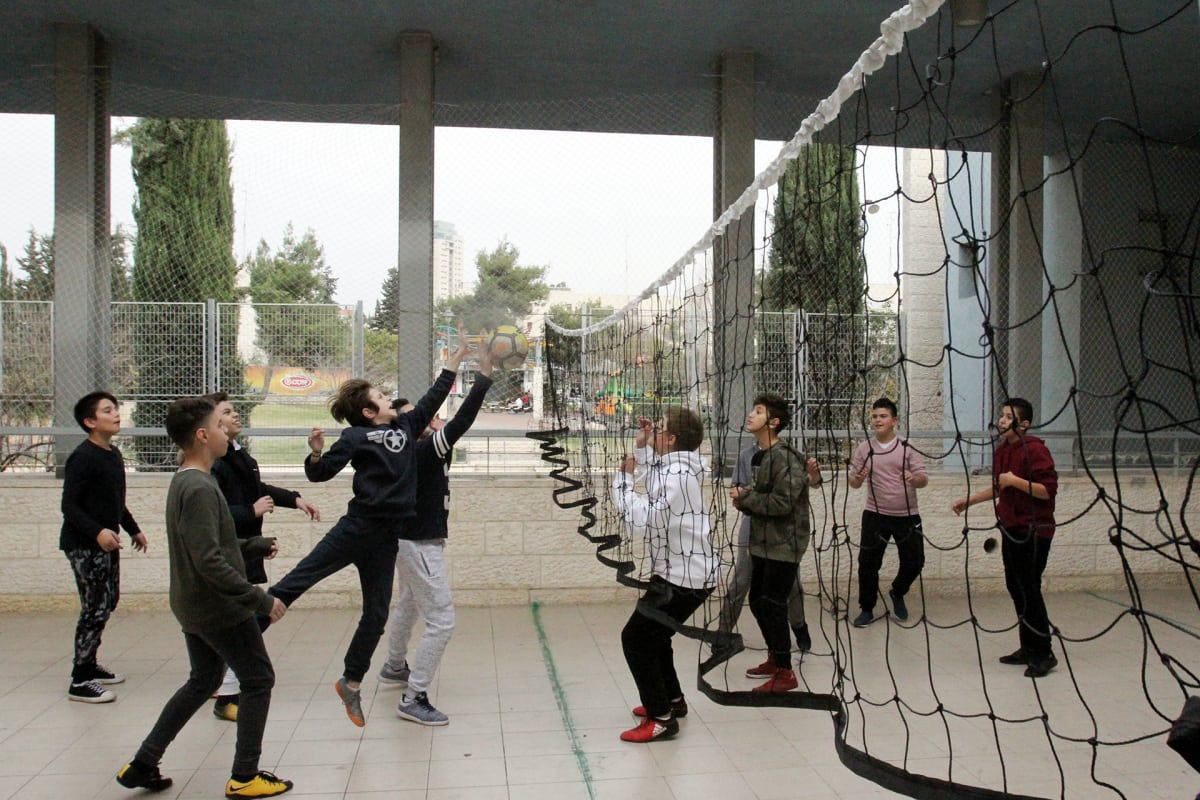 Oppilaat pelaavat lentopalloa yhteiskoulun pihalla Jerusalemissa.