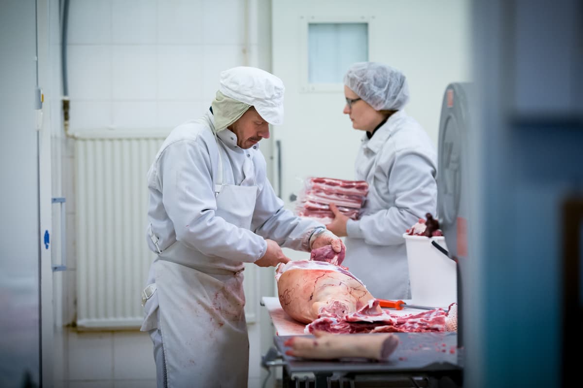 Lihanleikkaaja Mika Kujanmäki (vas) ja maatilayrittäjä Reetta Kivi (takana) lihanleikkuutiloissa, Sikala-tilateurastamo Kiven Säästöpossu, Karkkila, 14.2.2018.