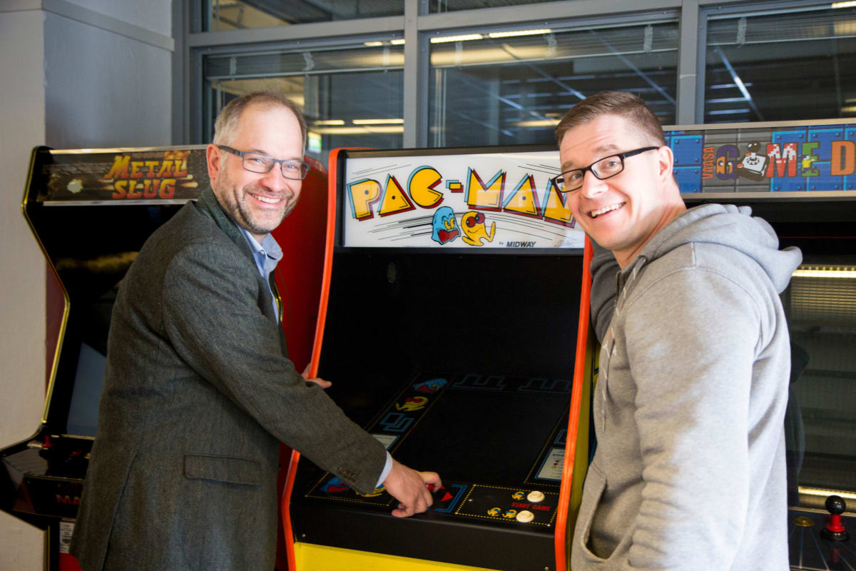 Taloustieteen professori Panu Kalmi ja pelitutkija Olli Raatikainen ikonisen Pac-Man -pelin äärellä.