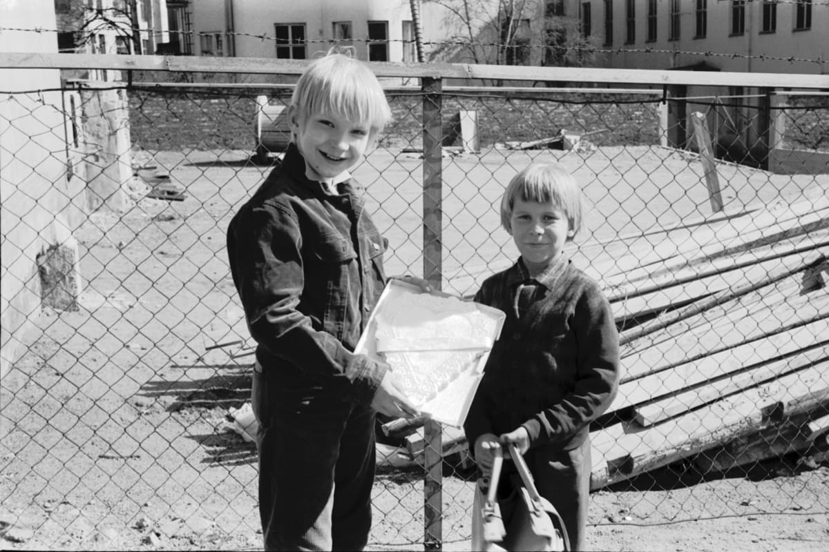 Kaksi poikaa myymässä sydämenmuotoisia kakkupapereita äitienpäivän kunniaksi.