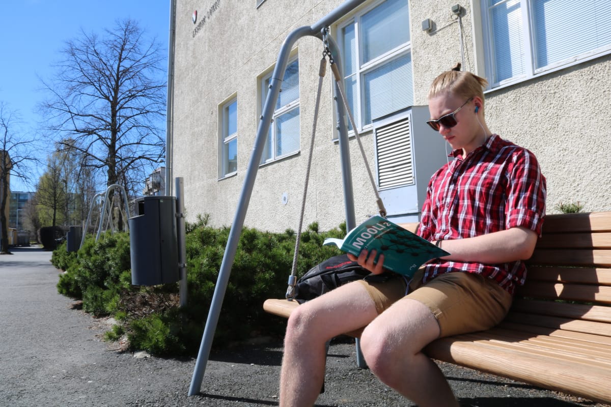 Poika istuu riippukeinussa ja lukee Mooli-kirjaa