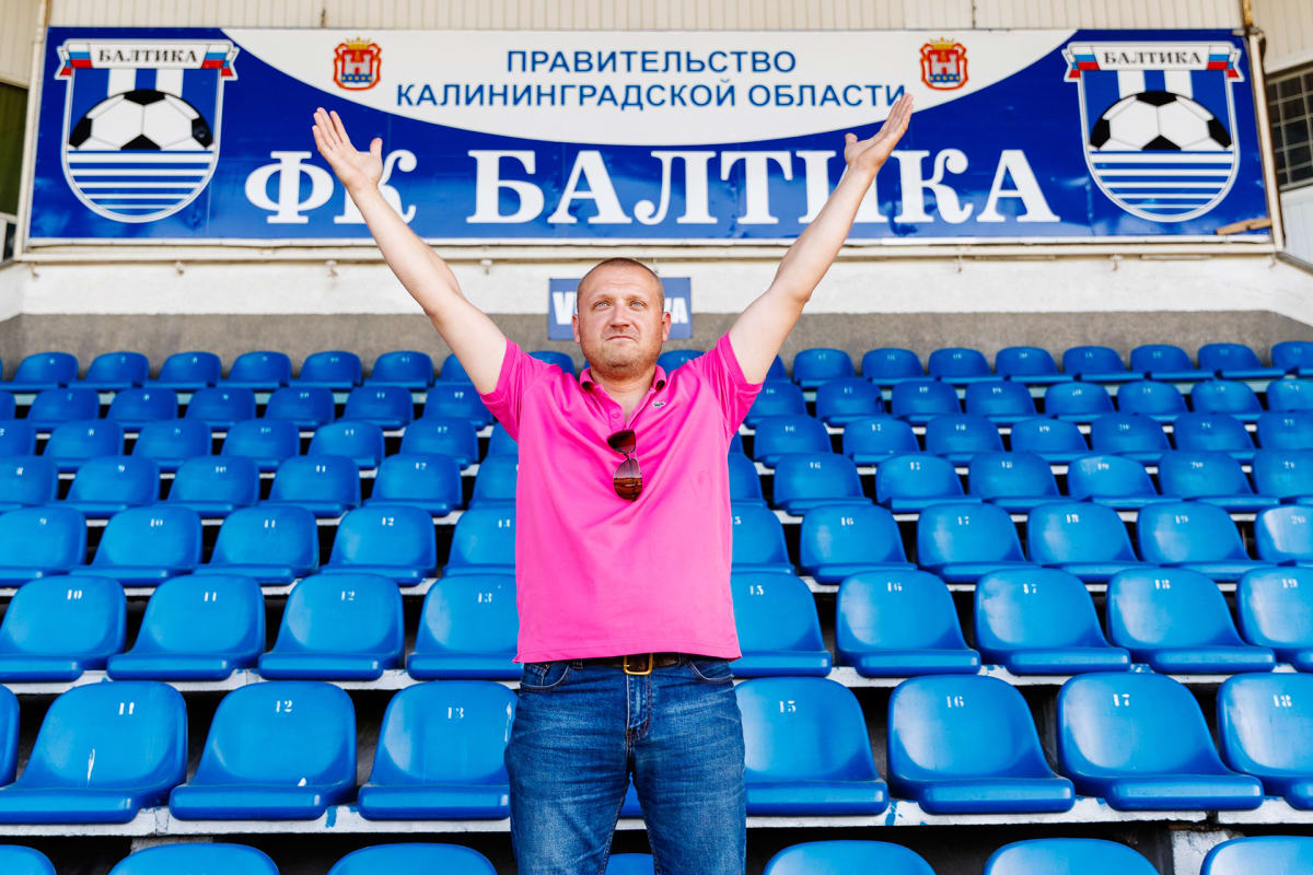 Vaaleanpunaiseen Lacosten pikee-paitaan ja farkkuihin sonnustautunut keski-ikäinen mies seisoo stadionin katsomossa kädet ylös nostettuina. Katsoman seinässä lukee joukkueen nimi: Baltika.