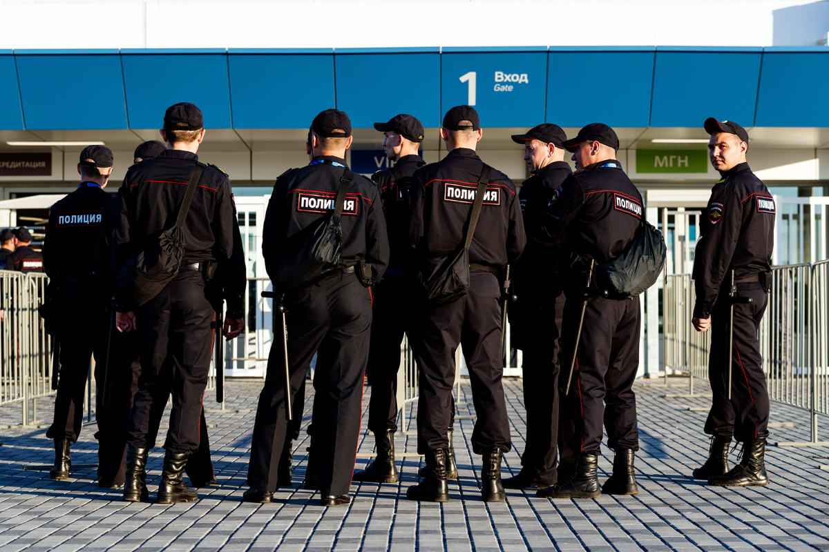 Joukko poliiseja seisoo stadionin porttien tuntumassa. Heillä on mustat univormut ja lippalakit. Vöistä riippuu pitkiä pamppuja.