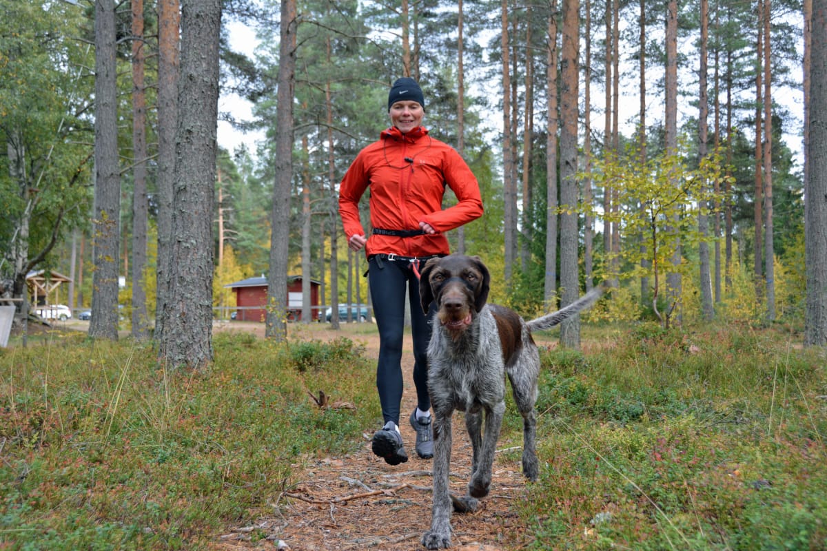 Teija Polso juoksee metsässä Vinku-koiransa kanssa.