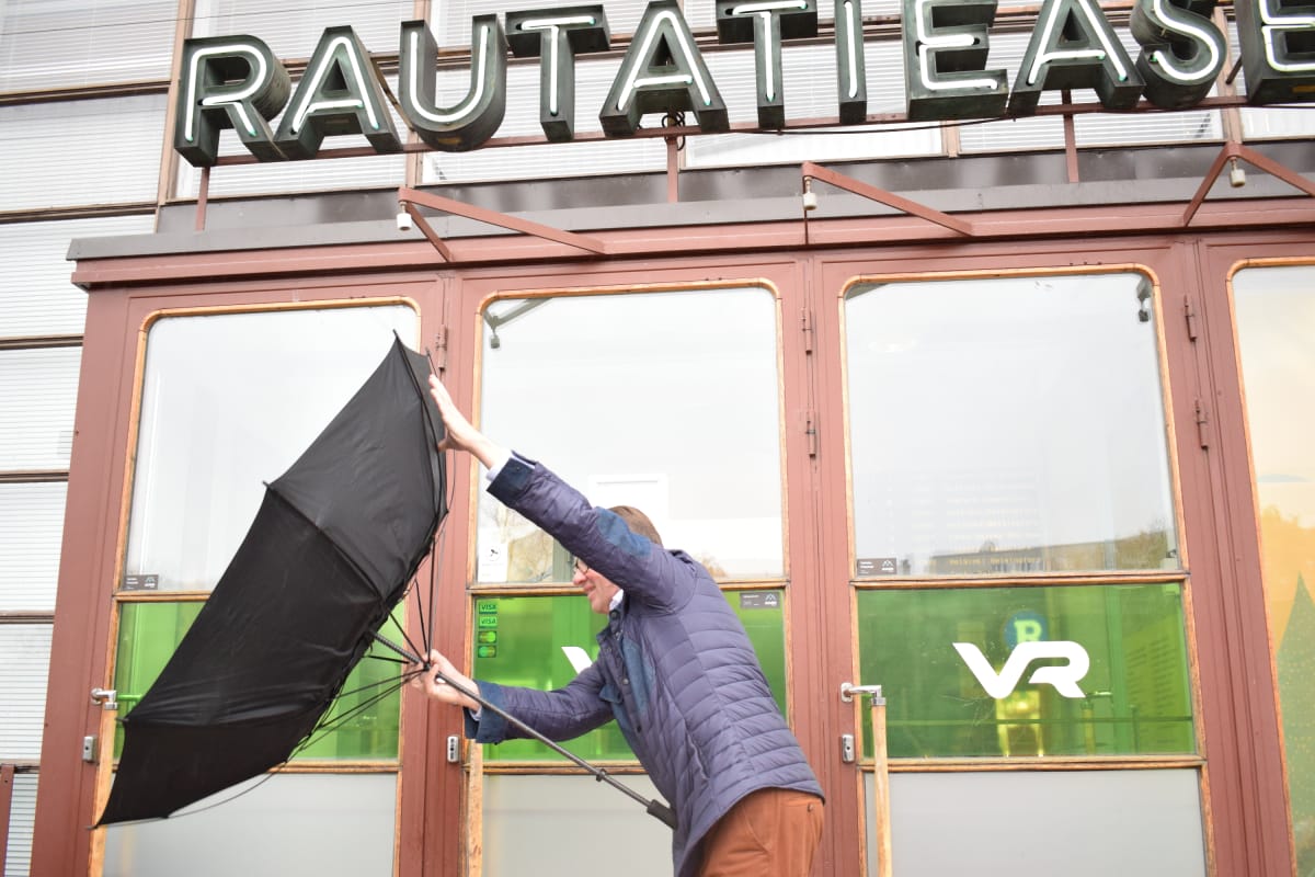 Kari Häkämies temppuilee sateenvarjan kanssa Turun asemalla.