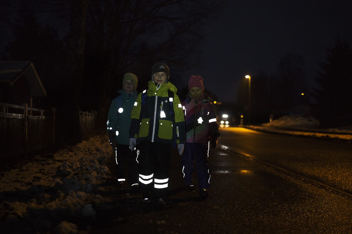 Heijastinta käyttäviä lapsia pimeällä kadulla.