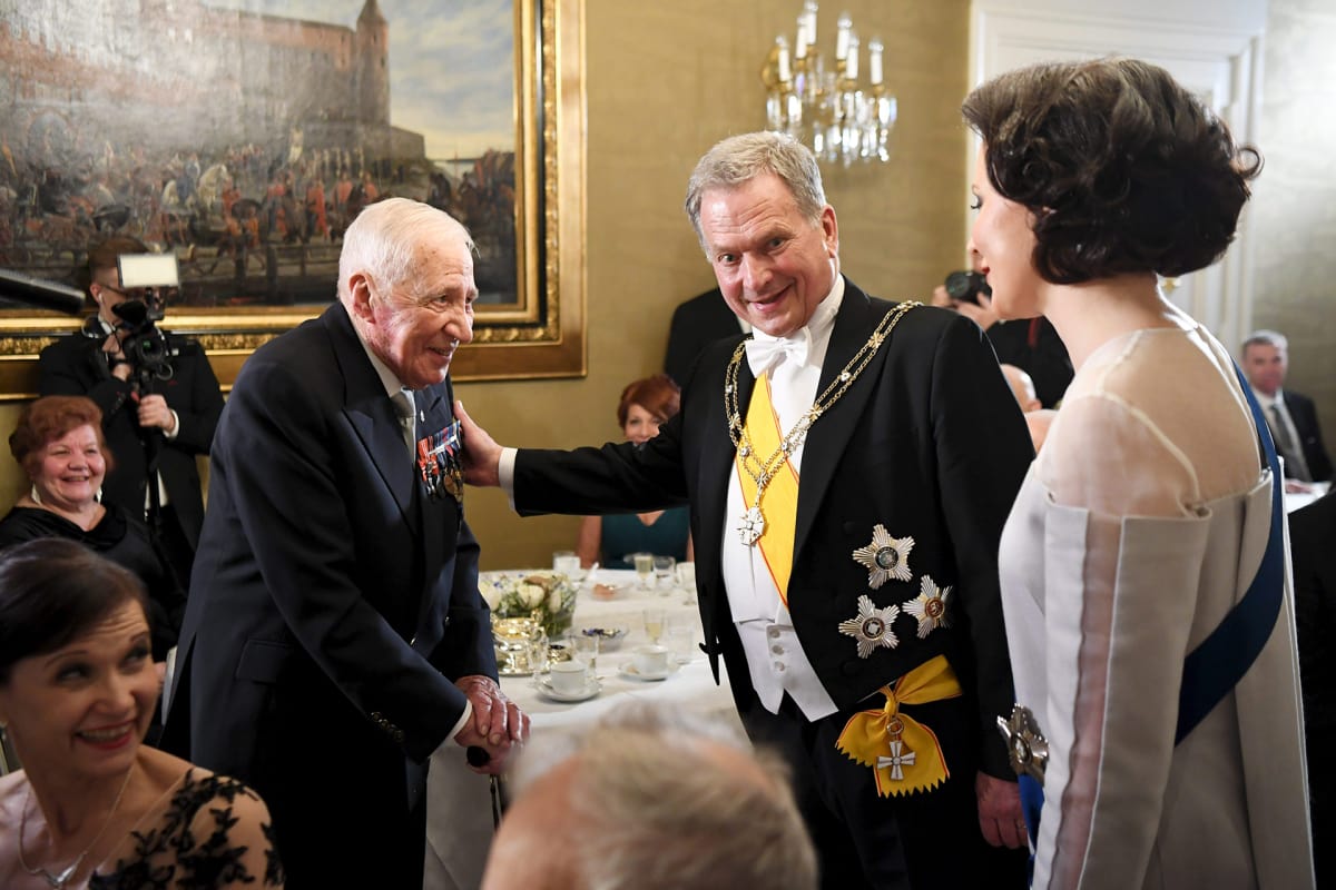 Presidentti Sauli Niinistö ja rouva Jenni Haukio keskustelevat veteraani Mauri Maunulan kanssa itsenäisyyspäivän vastaanotolla Helsingissä.
