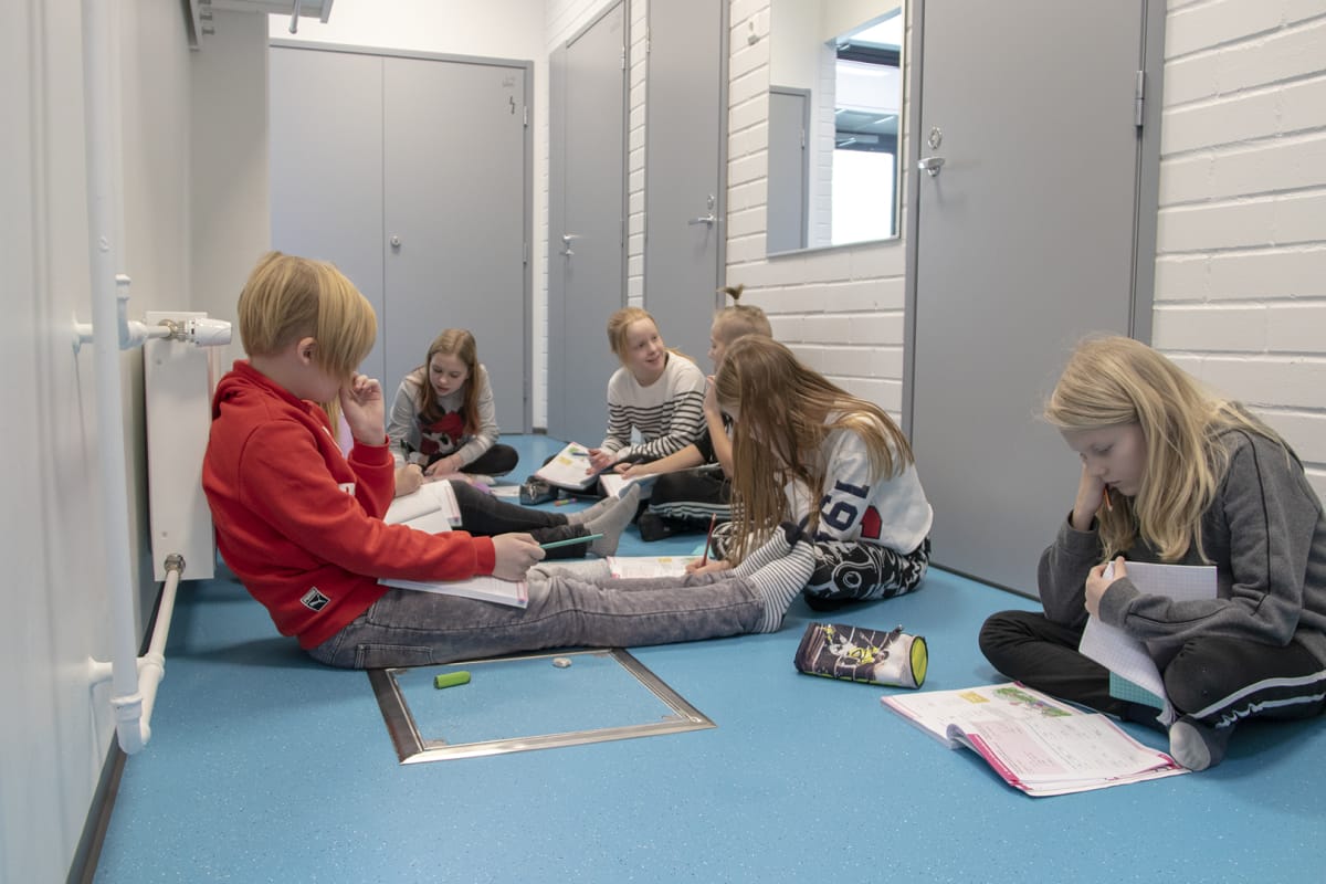 Oppilaita käytävällä istumassa Tyrnävän Rantaroustin koululla