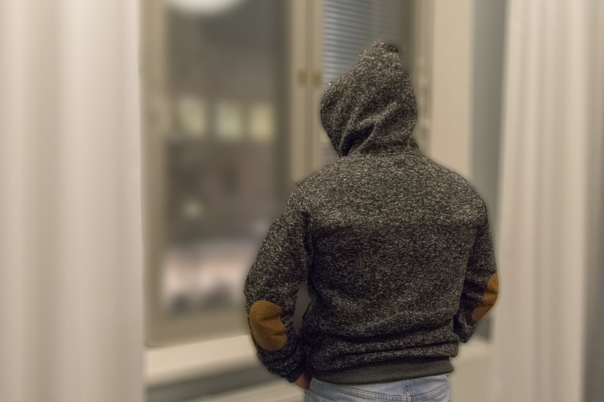 Anonyymi henkilö katsoo ikkunasta ulos.