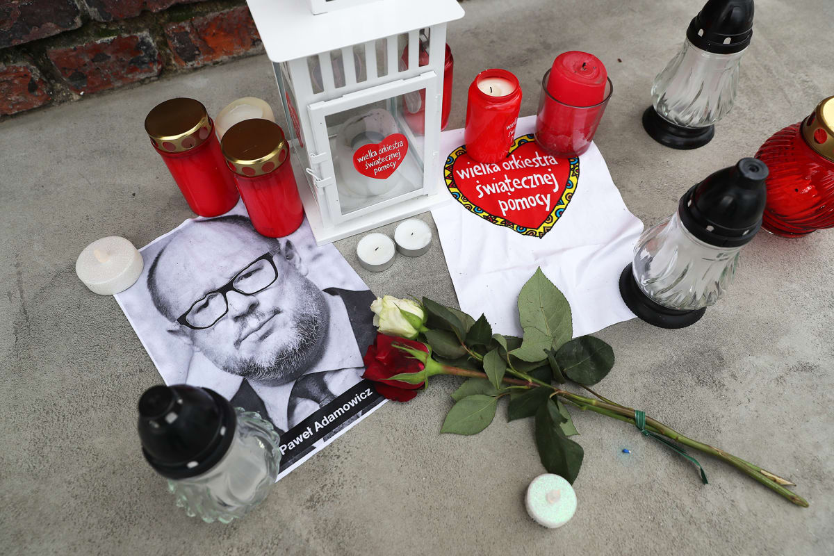 Kukkia ja kynttilöitä puukotetun pormestarin valokuvan ympärillä