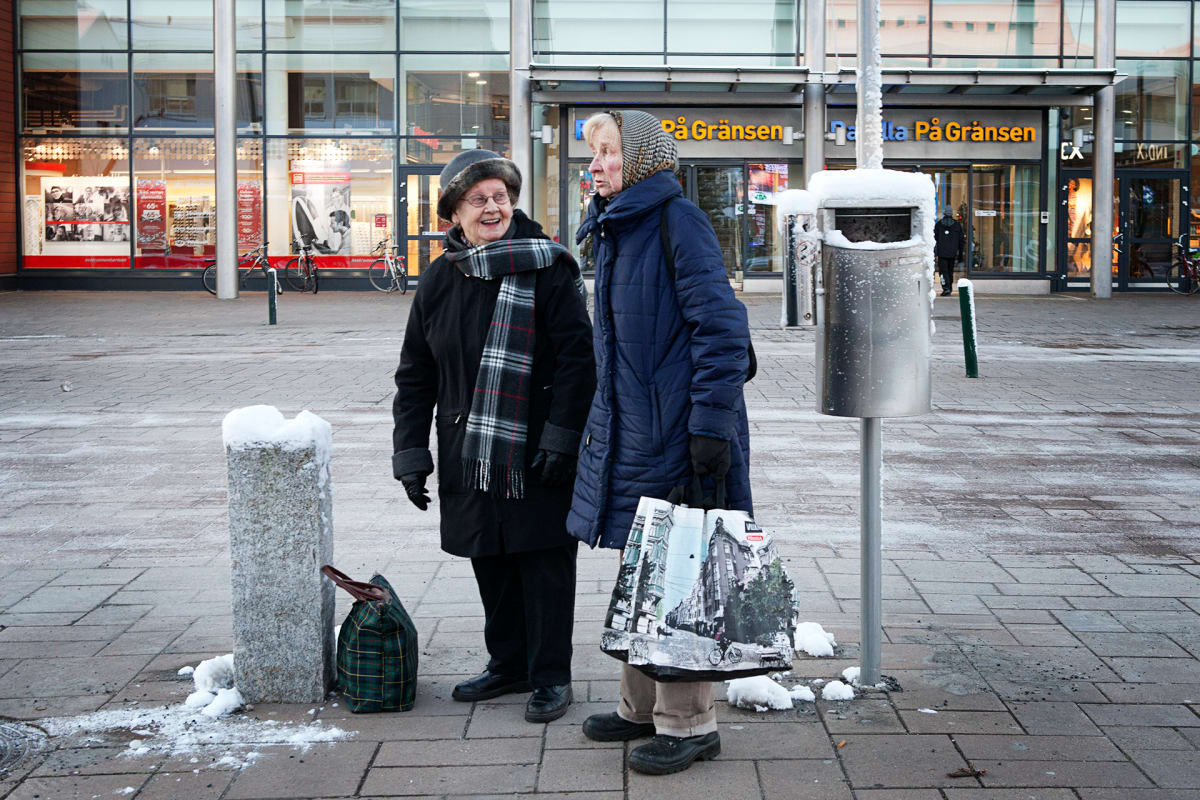 Kaksi rouvaa seisoo kauppakeskuksen edessä.