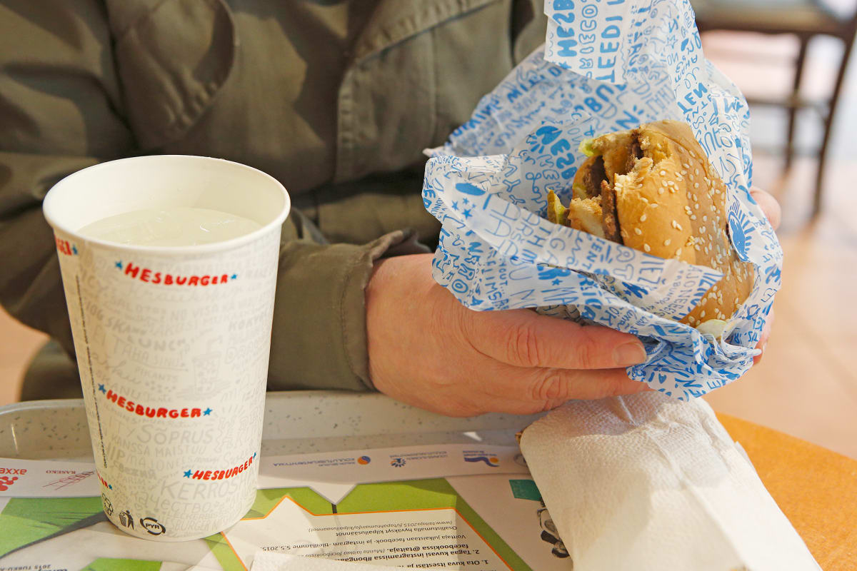 Mies syö hampurilaista Hesburgerissa.